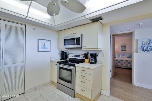 kitchen with stainless steel appliances, cream cabinets, light wood-type flooring, and ceiling fan