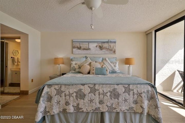 bedroom with connected bathroom, light hardwood / wood-style floors, ceiling fan, and a textured ceiling