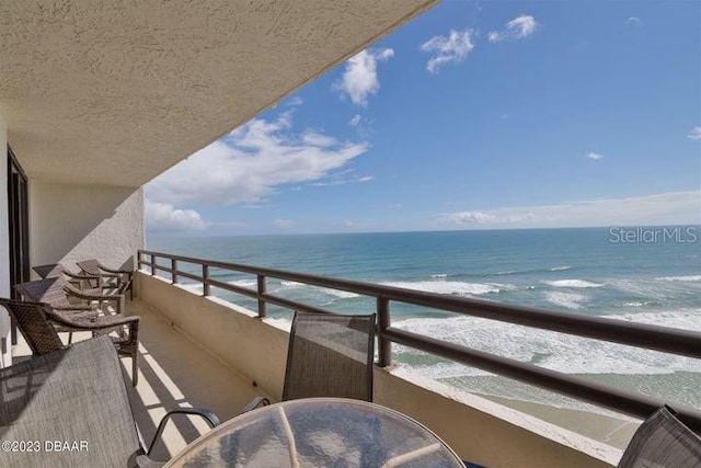 balcony featuring a view of the beach and a water view