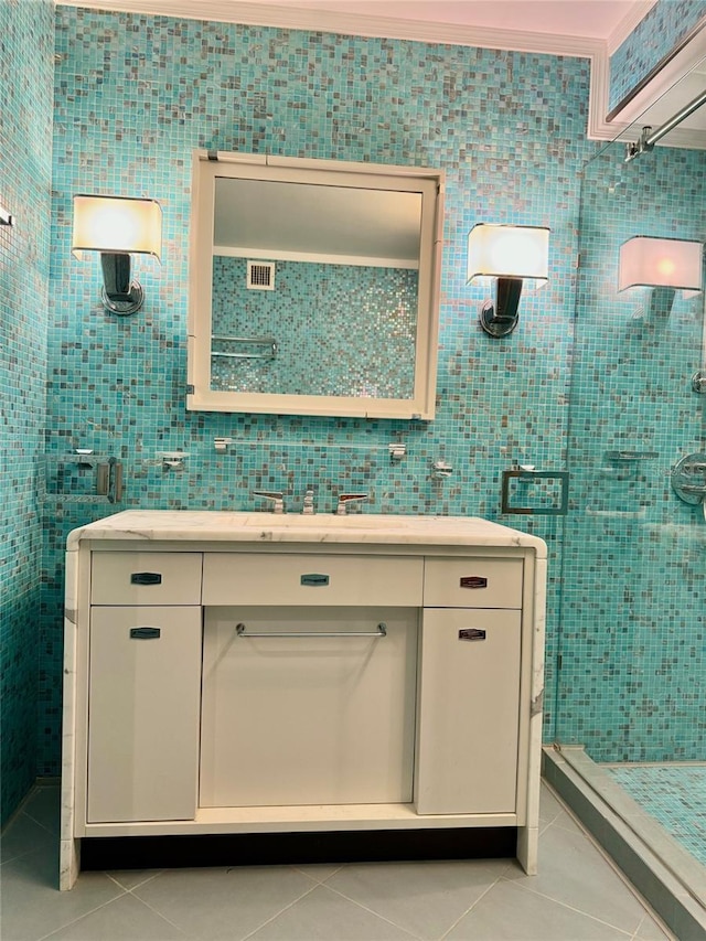 bathroom featuring tile walls, a shower, tile patterned floors, ornamental molding, and vanity