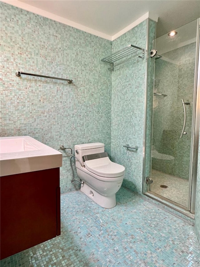 bathroom with tile walls, a shower with door, vanity, and toilet