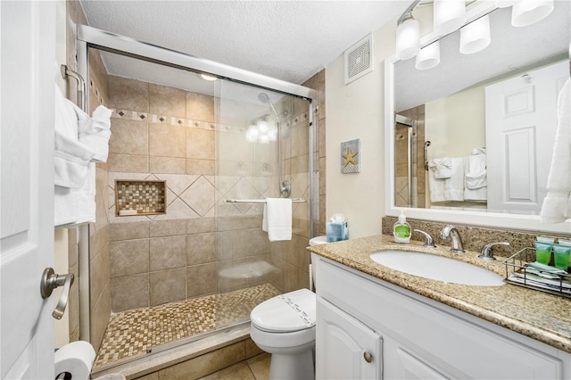 bathroom featuring tile patterned floors, an enclosed shower, a textured ceiling, vanity, and toilet