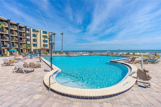 view of swimming pool featuring a water view and a patio area