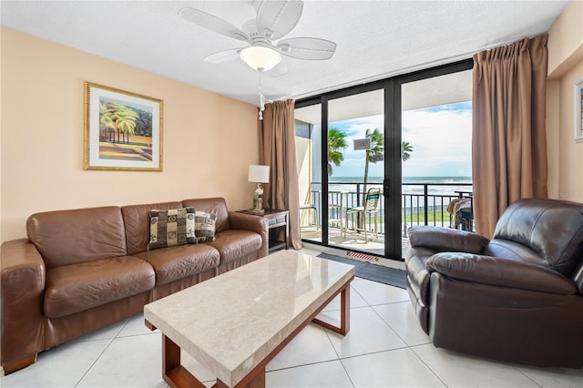 tiled living room with floor to ceiling windows, a textured ceiling, a water view, and ceiling fan