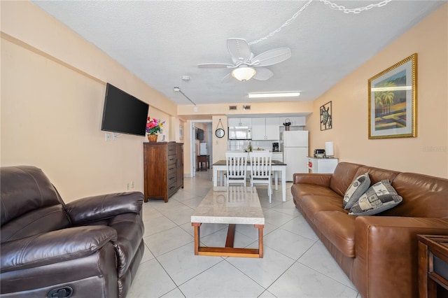 living room with ceiling fan, light tile patterned flooring, and a textured ceiling