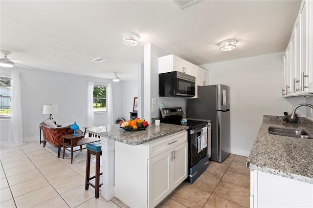 kitchen featuring sink, white cabinets, appliances with stainless steel finishes, light tile patterned floors, and light stone countertops