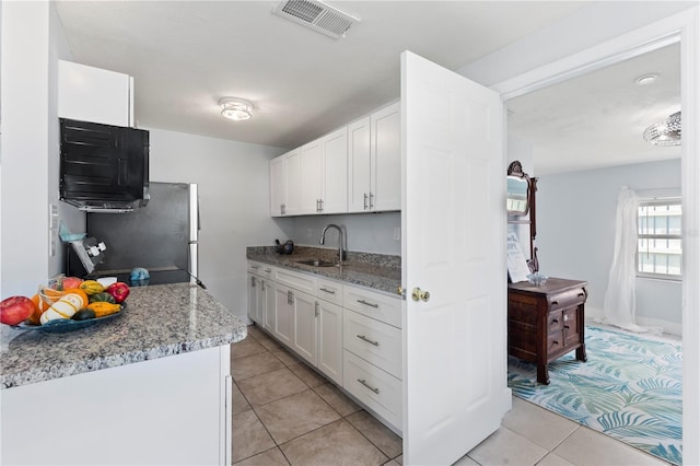 kitchen with white cabinetry, sink, light tile patterned floors, and light stone counters