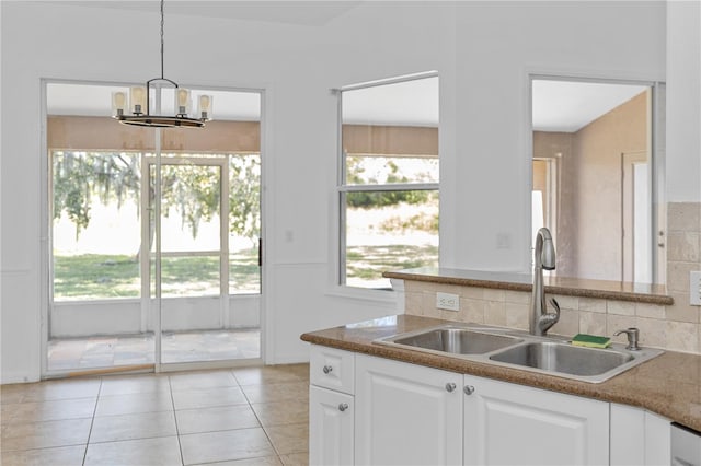 kitchen featuring sink, light tile patterned floors, decorative light fixtures, a chandelier, and white cabinetry