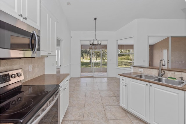 kitchen with appliances with stainless steel finishes, white cabinetry, a notable chandelier, and sink