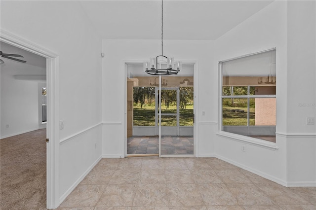 unfurnished dining area with ceiling fan with notable chandelier and light carpet