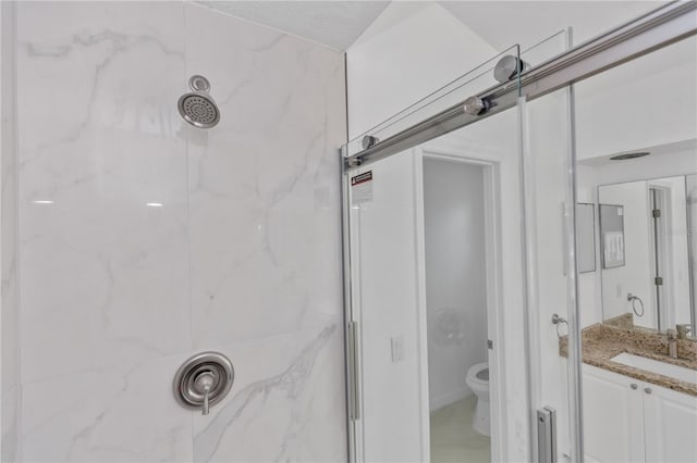 bathroom featuring a tile shower, vanity, a textured ceiling, and toilet