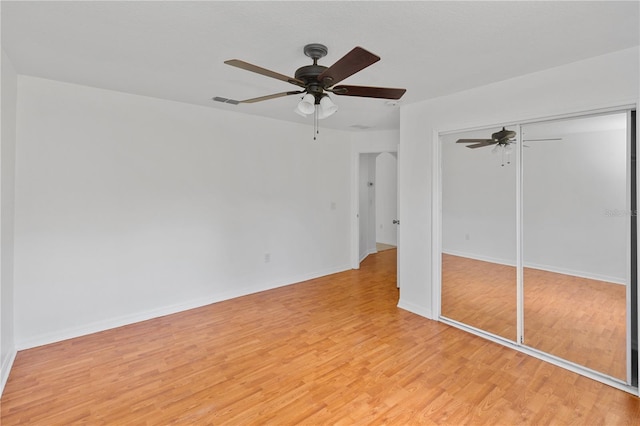 unfurnished bedroom featuring a closet, light hardwood / wood-style flooring, and ceiling fan