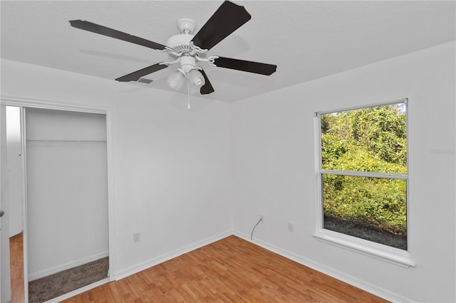 unfurnished bedroom featuring ceiling fan, a closet, and hardwood / wood-style flooring