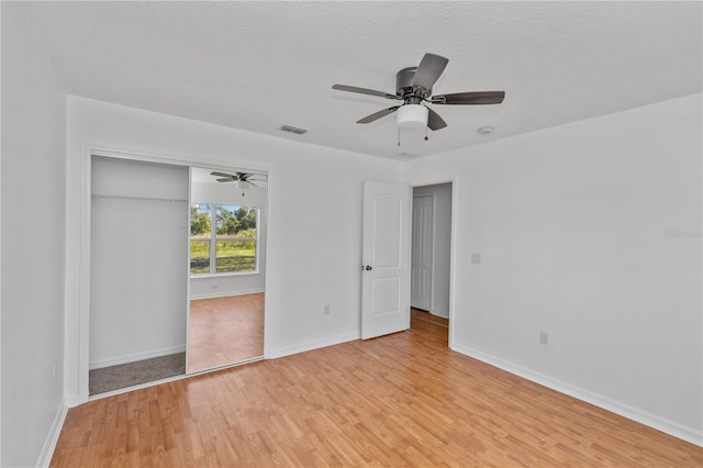 unfurnished bedroom with a textured ceiling, a closet, light hardwood / wood-style floors, and ceiling fan