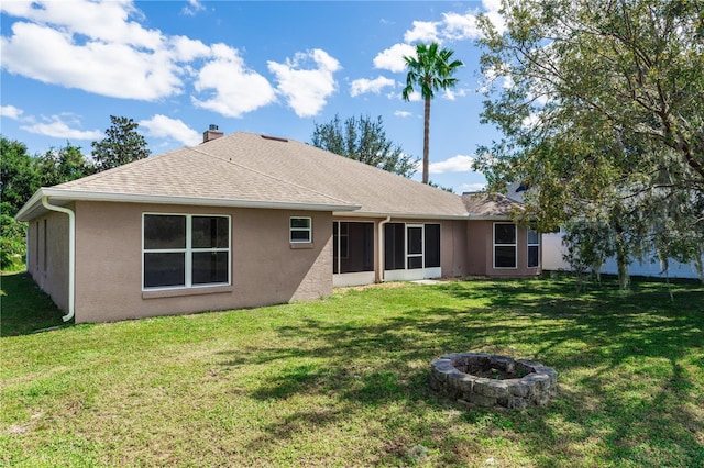 back of property with a yard and a fire pit