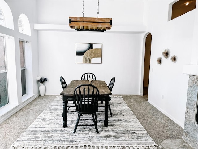 carpeted dining room with a towering ceiling