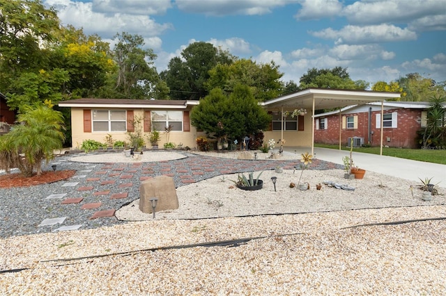 ranch-style home featuring concrete driveway, an attached carport, and central air condition unit