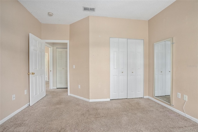 unfurnished bedroom with light colored carpet and a textured ceiling