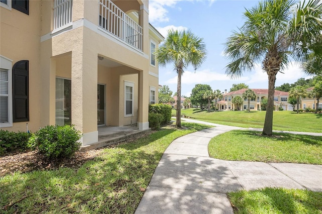 view of side of home with a balcony and a yard