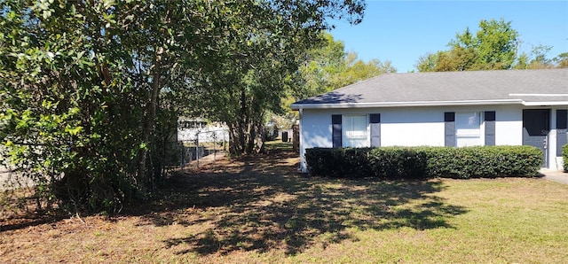 view of home's exterior with a yard, stucco siding, and fence