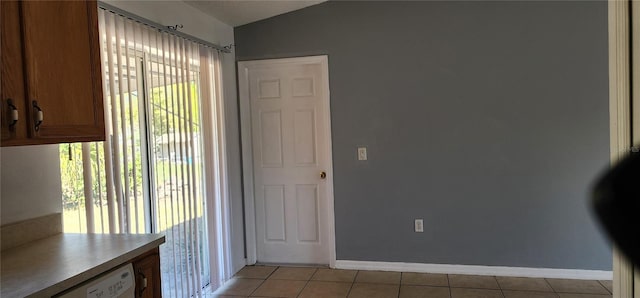 interior space featuring vaulted ceiling, light tile patterned floors, and baseboards