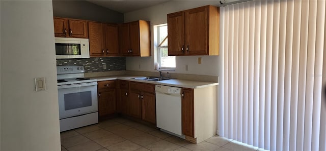 kitchen featuring light countertops, brown cabinets, light tile patterned flooring, white appliances, and a sink