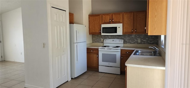 kitchen featuring white appliances, brown cabinetry, light tile patterned flooring, a sink, and backsplash