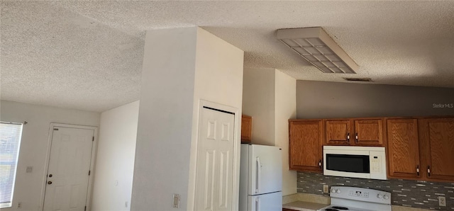 kitchen featuring white appliances, brown cabinetry, visible vents, lofted ceiling, and a textured ceiling