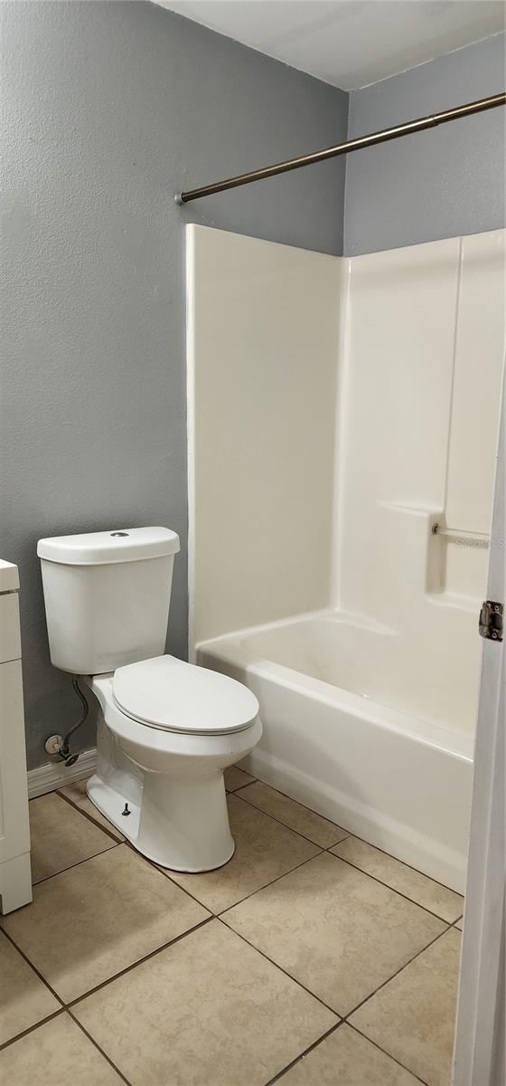 bathroom featuring tile patterned floors, toilet, and bathing tub / shower combination