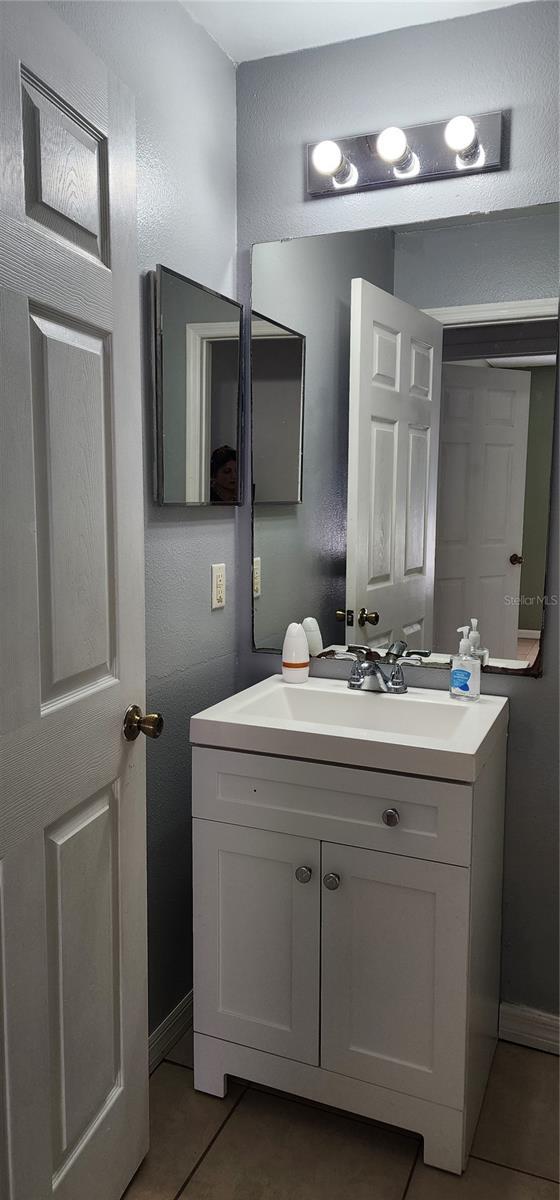 bathroom with baseboards, vanity, and tile patterned flooring