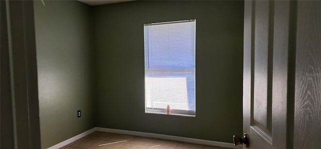 empty room featuring light tile patterned flooring and baseboards