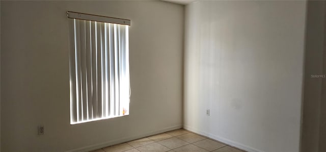 unfurnished room with light tile patterned flooring and baseboards