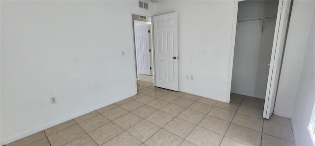 unfurnished bedroom with light tile patterned flooring, baseboards, visible vents, and a closet