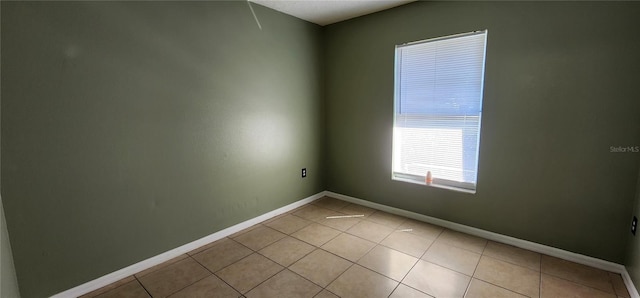 spare room featuring light tile patterned flooring and baseboards