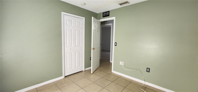 unfurnished bedroom with light tile patterned floors, baseboards, visible vents, and a closet