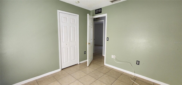 unfurnished bedroom featuring light tile patterned floors, a closet, baseboards, and visible vents