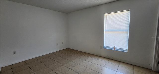 spare room with light tile patterned flooring and a textured ceiling