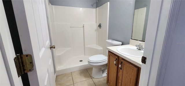 bathroom featuring tile patterned flooring, vanity, toilet, and a shower