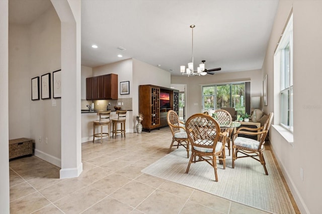 dining space with ceiling fan with notable chandelier and light tile patterned floors