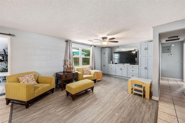 living room featuring light wood-type flooring, a textured ceiling, and ceiling fan