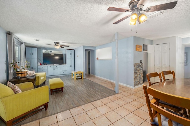 living room featuring light wood-type flooring, a textured ceiling, and ceiling fan