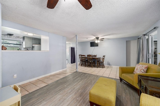 living room with light wood-type flooring, ceiling fan, and a textured ceiling