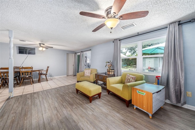 living room featuring ceiling fan, a textured ceiling, and light hardwood / wood-style floors