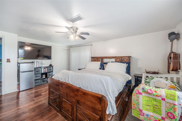 bedroom with ceiling fan, stainless steel refrigerator, and dark hardwood / wood-style flooring