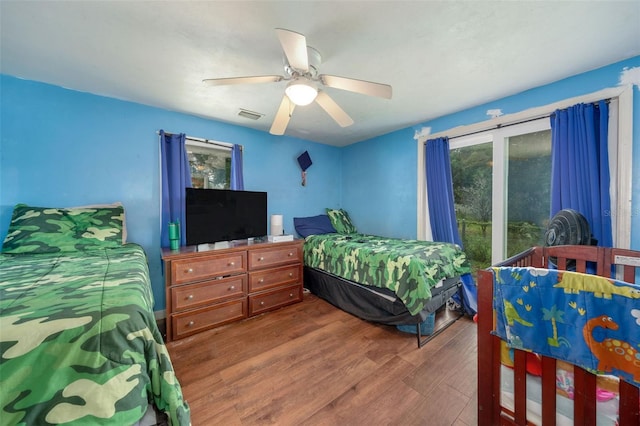 bedroom with ceiling fan, dark hardwood / wood-style floors, and access to exterior