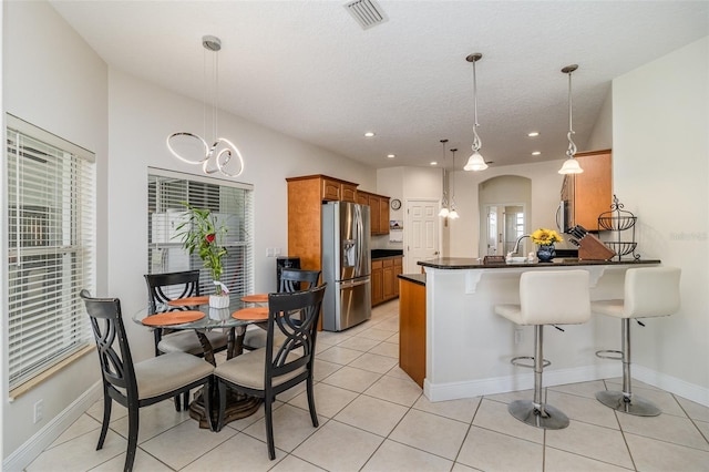 929 Hialeah St, Rockledge, FL 32955 - kitchen with dark countertops, brown cabinets, a peninsula, visible vents, and stainless steel refrigerator with ice dispenser