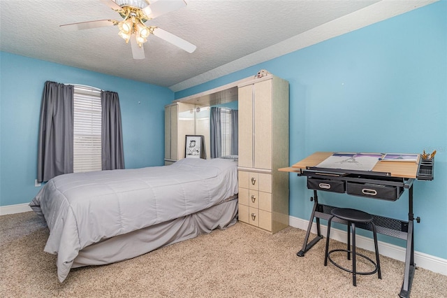 bedroom with ceiling fan, light colored carpet, and a textured ceiling