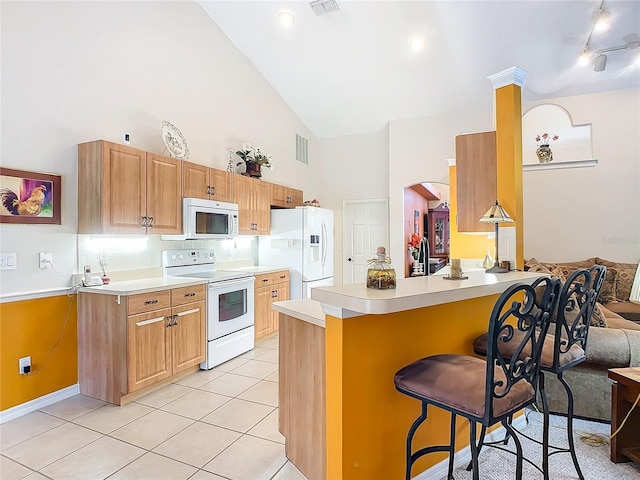 kitchen featuring a breakfast bar, light tile patterned flooring, white appliances, and high vaulted ceiling