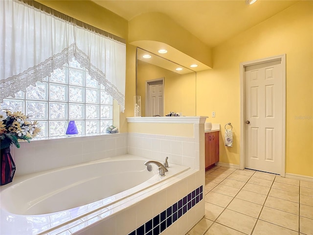 bathroom with tile patterned floors, vanity, tiled tub, and vaulted ceiling