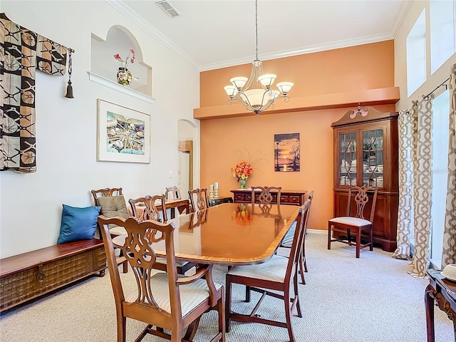 carpeted dining room featuring ornamental molding and a chandelier